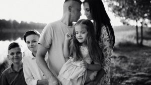 A serene black and white portrait of a family standing by a lake.